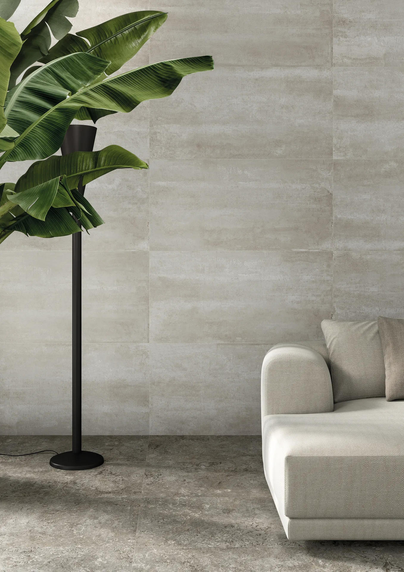 Wohnzimmerecke mit graubeiger Steinoptik-Wand, hellem Sofa und Blattpflanze, Fliesenformat 60×120 cm.