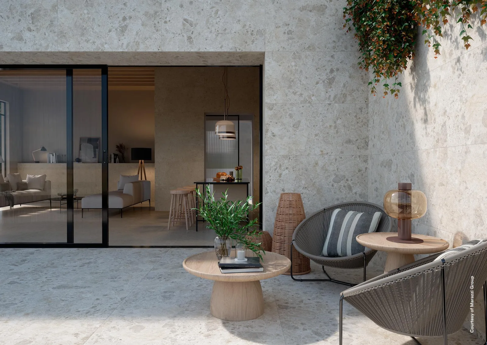 Überdachte Terrasse mit hellem Terrazzo-Optik-Boden, Wand in greigefarbener Steinoptik, Loungesessel und Pflanzen.
