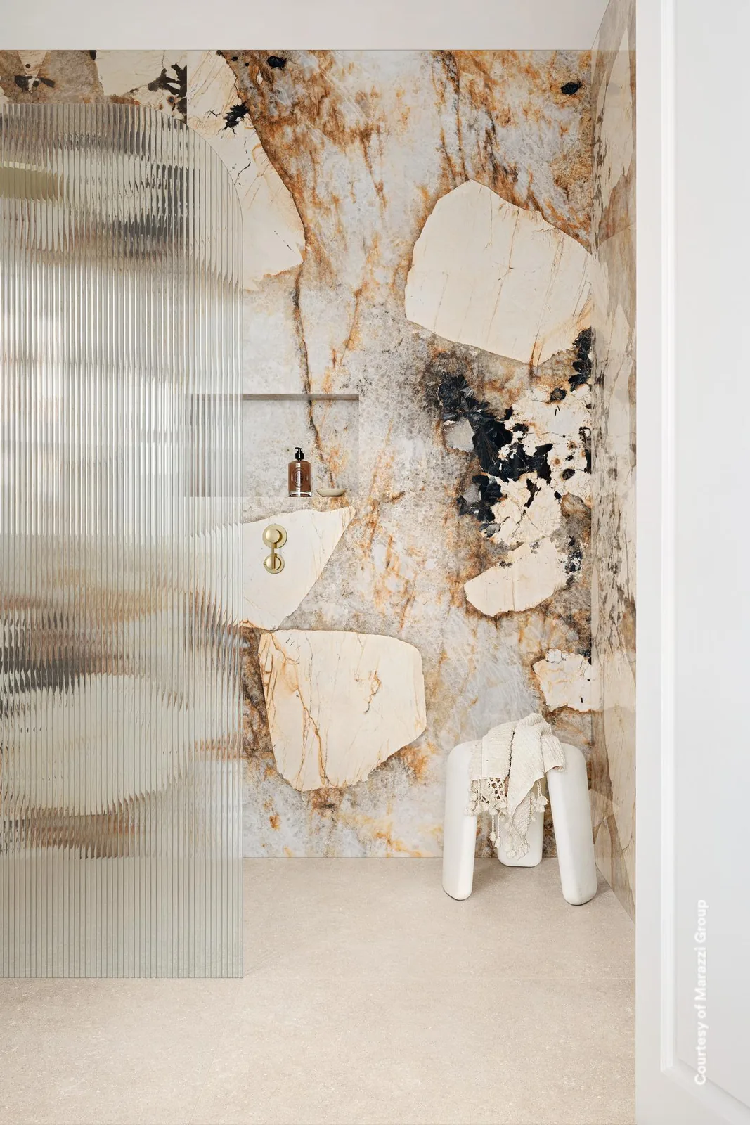 Dusche mit Wand in cremebeiger Marmoroptik mit rostbraunen Adern und dunklen Einschlüssen, geriffelte Glaswand.
