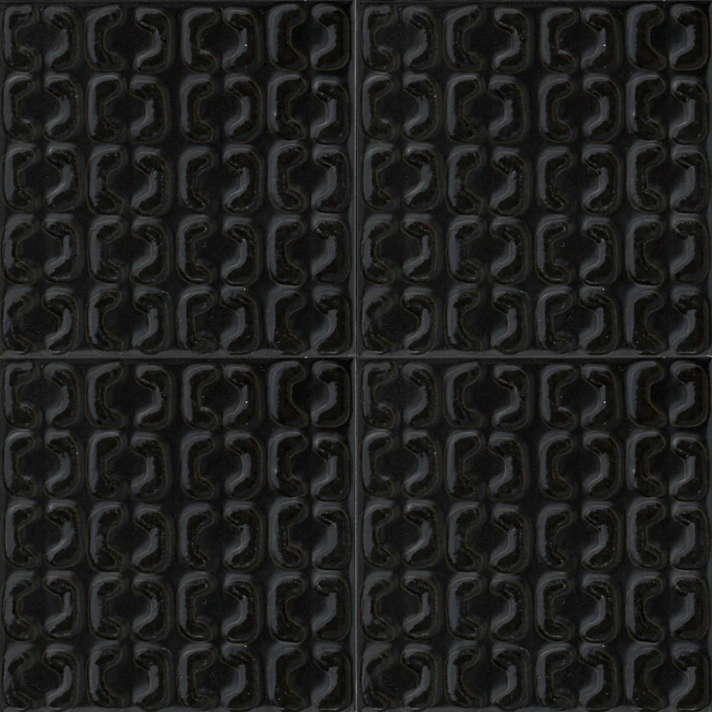 Vier schwarze Reliefliesen 15x15 cm, seidenmatt, mit erhabenem Muster aus ineinandergreifenden, gerundeten Bogenformen.