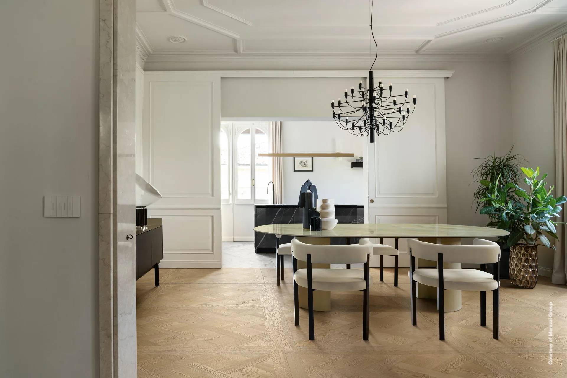 Esszimmer mit ovalem Tisch und hellen Rundstühlen auf hellbeigem Kassettenparkett-Boden in Holzoptik.