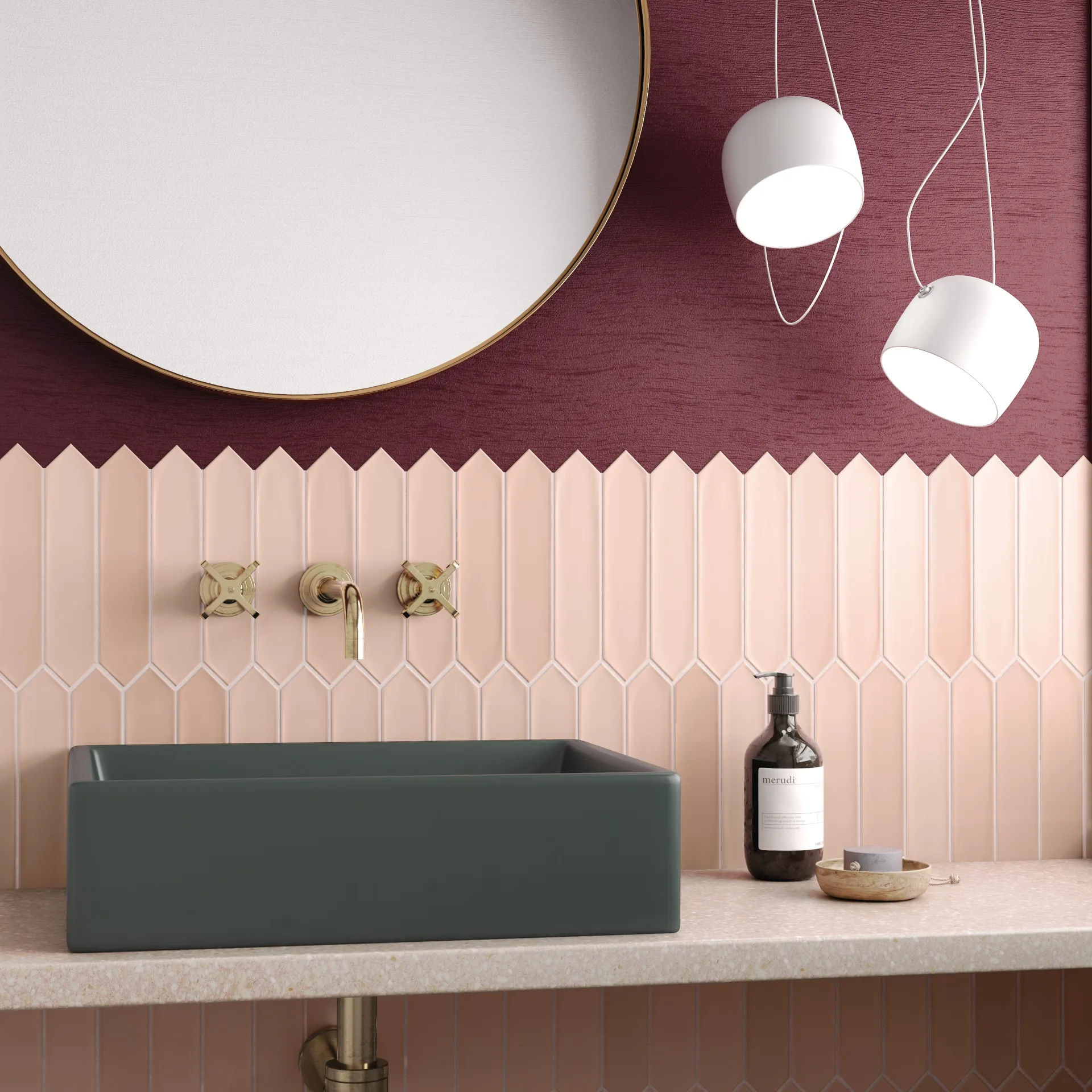 Bad mit zartrosa, spitz zulaufenden Wandfliesen unter bordeauxroter Wand, rundem Spiegel und grauem Becken.