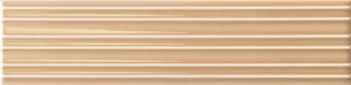 Rechteckige Wandfliese in sanftem Karamellbeige, glänzend, mit parallelem Rillenrelief, im Format 6x24,6 cm.