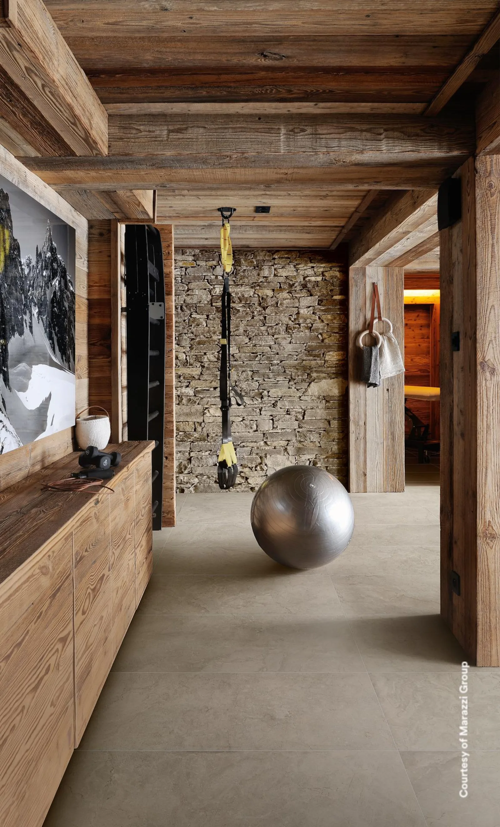 Langer Flur mit Holzbalkendecke, Steinwand und durchgehend hellbeigem Bodenbelag