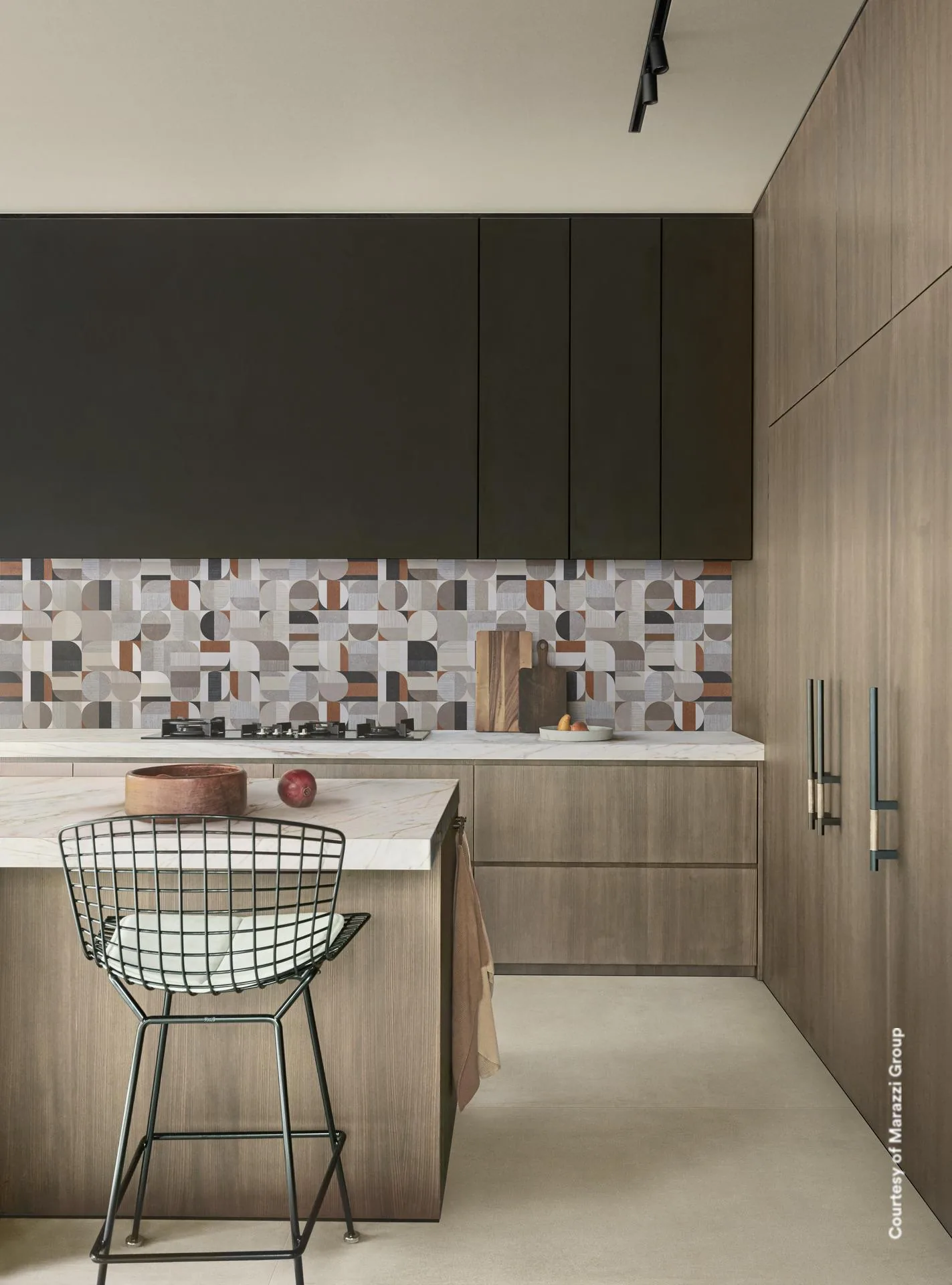 Küche mit geometrisch gemusterter Rückwand in Beige, Grau und Rostrot, dunklen Hängeschränken und Kochinsel aus Holz