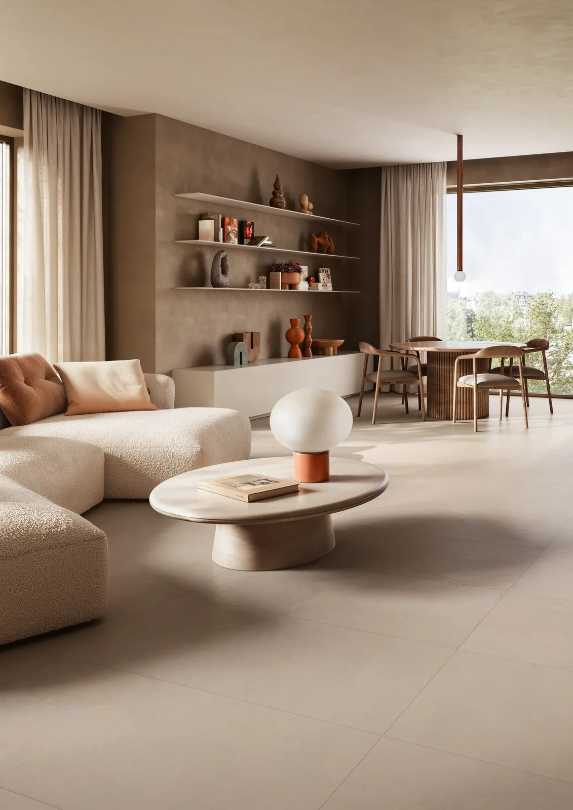 Wohnzimmer mit taupefarbenem Betonoptik-Boden, hellem Sofa, rundem Couchtisch und Regalwand im Hintergrund