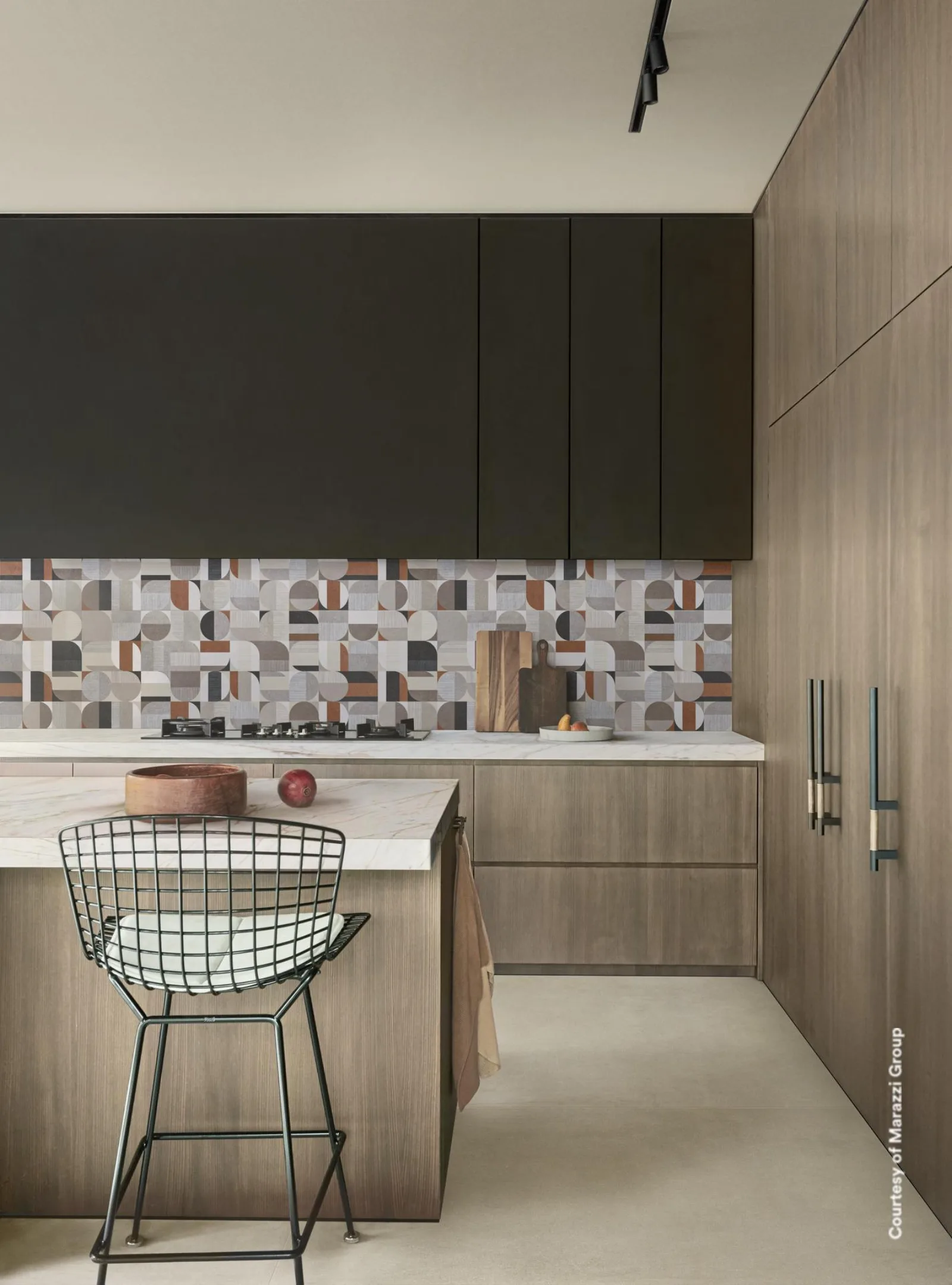 Küche mit Holzfronten, Kochinsel und geometrisch gemustertem Fliesenspiegel auf beigegrauem Betonoptik-Boden.