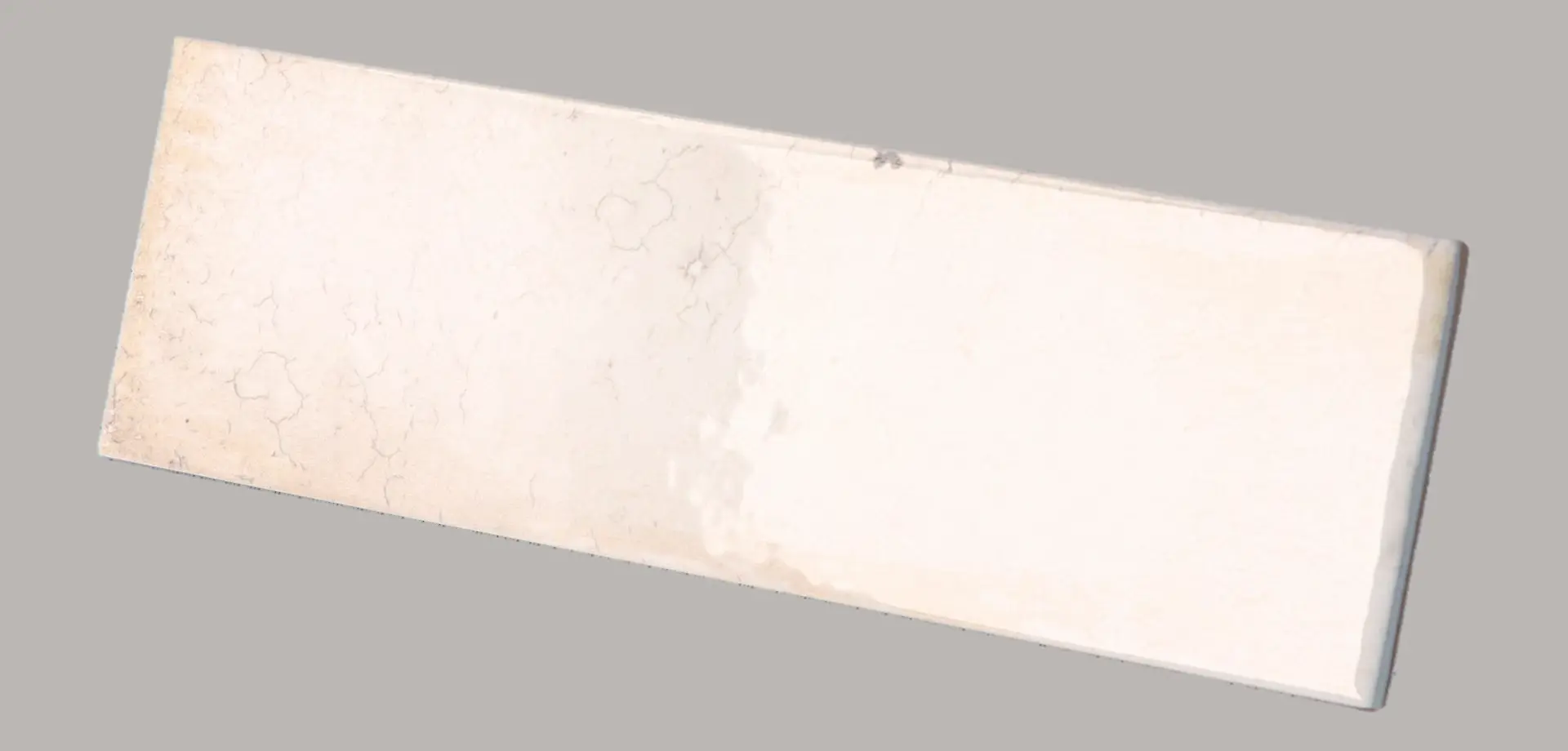 Hanoi Wandfliese in White Glasur, Format 6,5x20 cm, schräge Studio Aufnahme mit sichtbarem Glasurglanz.