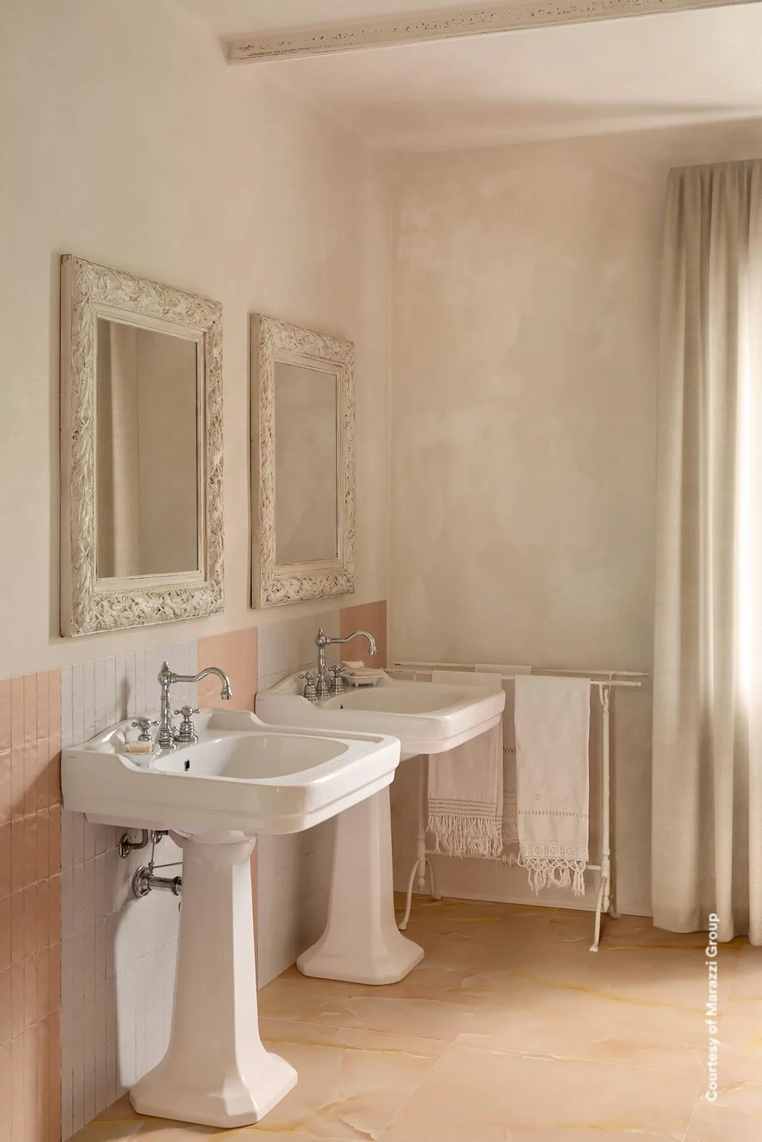 Bad mit zwei Standwaschbecken, rosa Wandfliesen und Boden in pfirsichbeiger Marmoroptik mit goldgelben Adern.