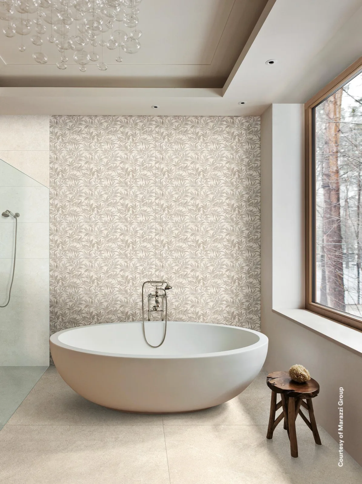 Bad mit freistehender Badewanne vor einer Wand im hellen Blättermuster, großem Fenster und hellem Fliesenboden.