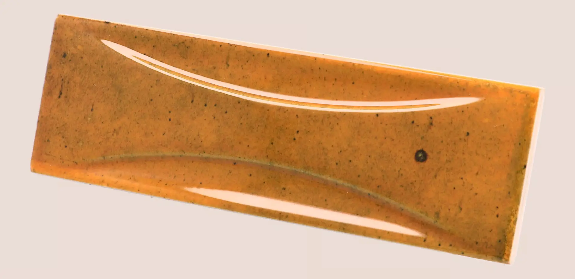 Hanoi Wandfliese in Burnt Red Glasur, Format 6,5x20 cm, schräge Studio Aufnahme mit sichtbarem Glasurglanz.