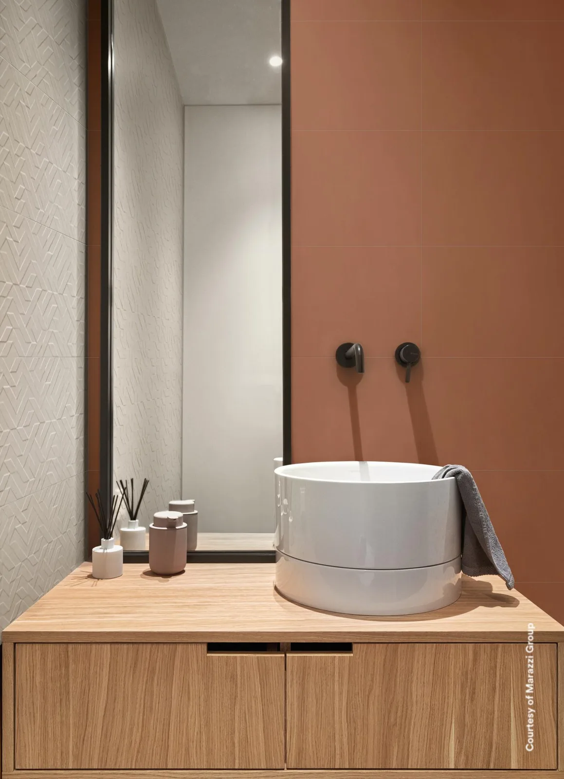Gäste-WC mit runder Waschschale auf Holzkonsole vor terrakottafarbener Wand, links weiße Reliefwand, hoher Spiegel.