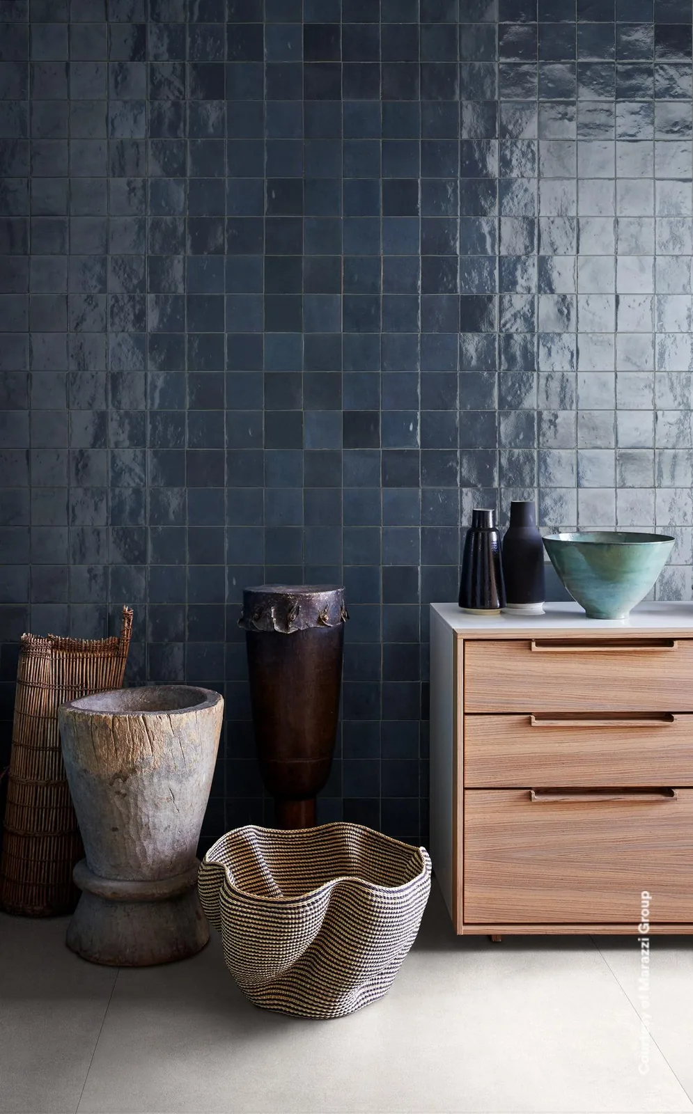 Wand aus Marazzi Zellige China 10x10 cm in glänzendem Marineblau, davor Holzkommode und Keramikgefäße