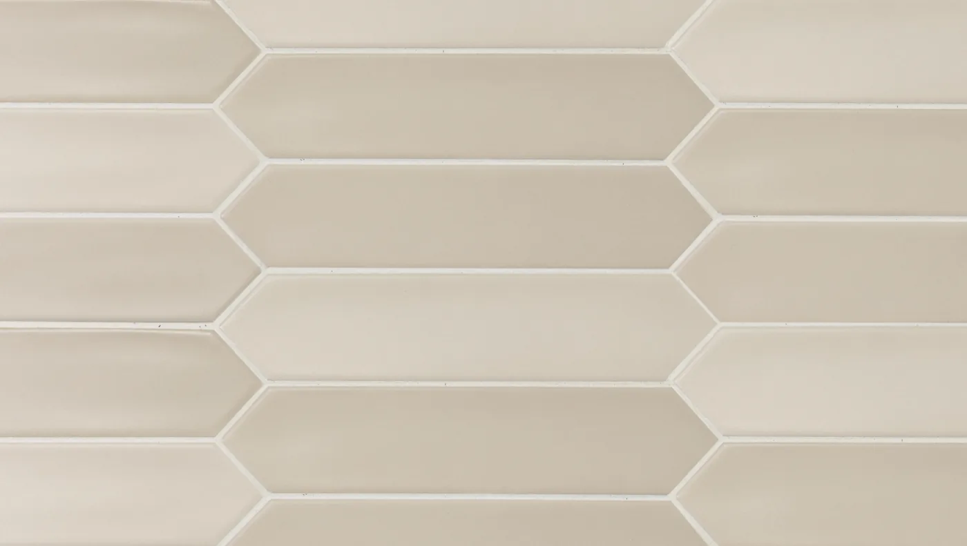 Beige-greige Wandfliese in spitzovaler Riemchenform 5×25 cm, matt glasiert mit warmer, leichter Farbschattierung.