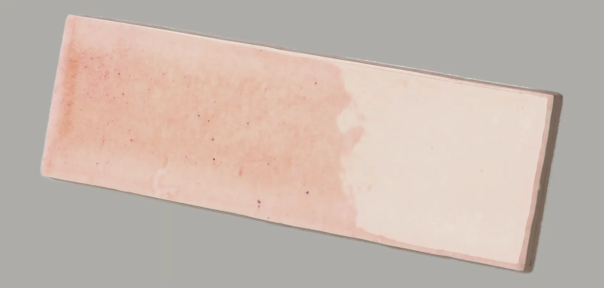 Hanoi Wandfliese in Pink Glasur, Format 5,1x16,1 cm, schräge Studio Aufnahme mit sichtbarem Glasurglanz.