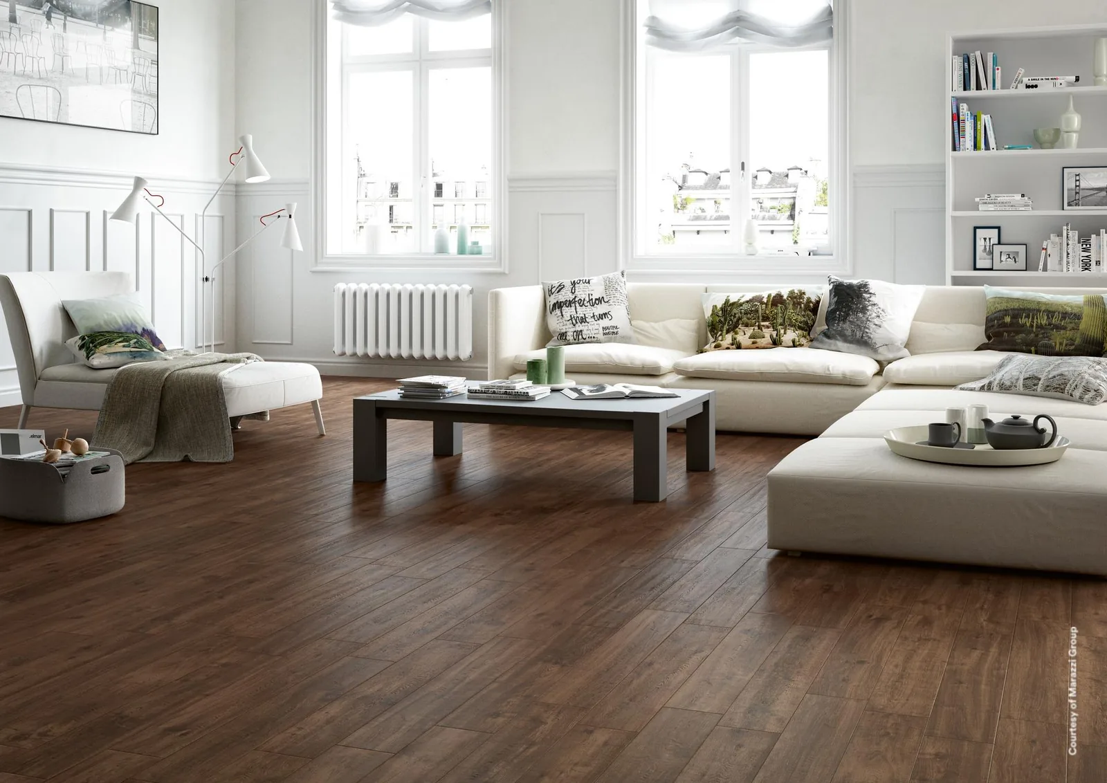 Wohnzimmer mit weißem Ecksofa und dunklem Couchtisch auf Dielenfliesen in dunklem Graubraun