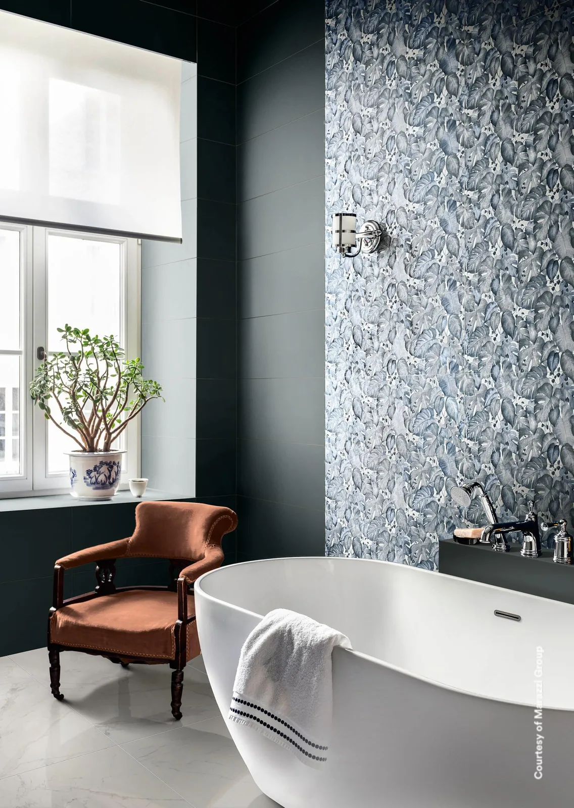 Bad mit freistehender Wanne vor dunkler blaugrauer Wand und einer Wandfläche aus Fliesen mit blaugrauem Blattmuster.