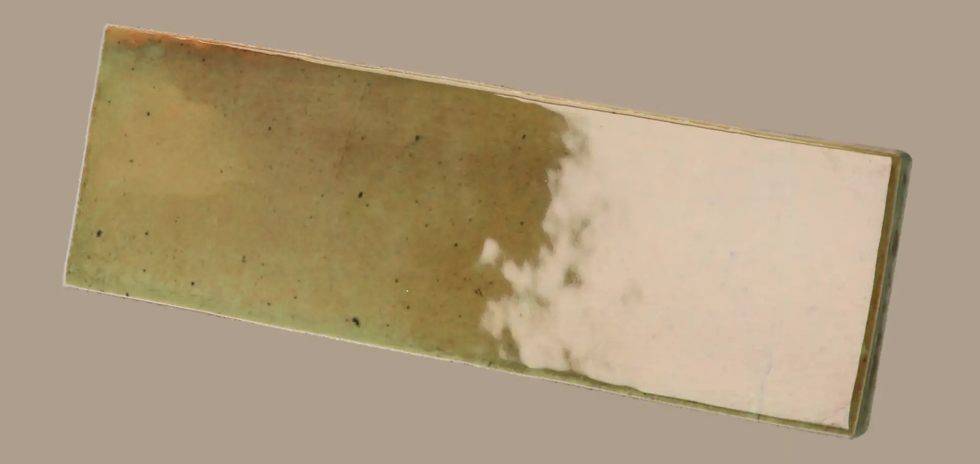 Hanoi Wandfliese in Wild Olive Glasur, Format 5,1x16,1 cm, schräge Studio Aufnahme mit sichtbarem Glasurglanz.