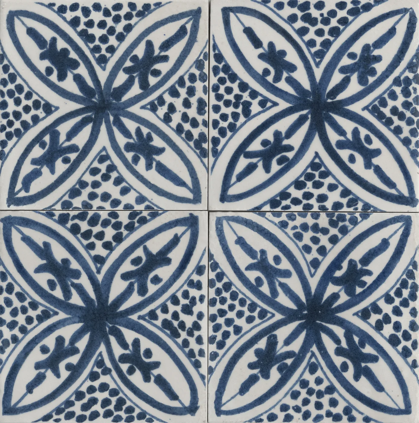 Vier glänzende Fliesen 15x15 cm mit großem blauem Blattstern aus vier Spitzblättern und gepunktetem Grund in Weiß.
