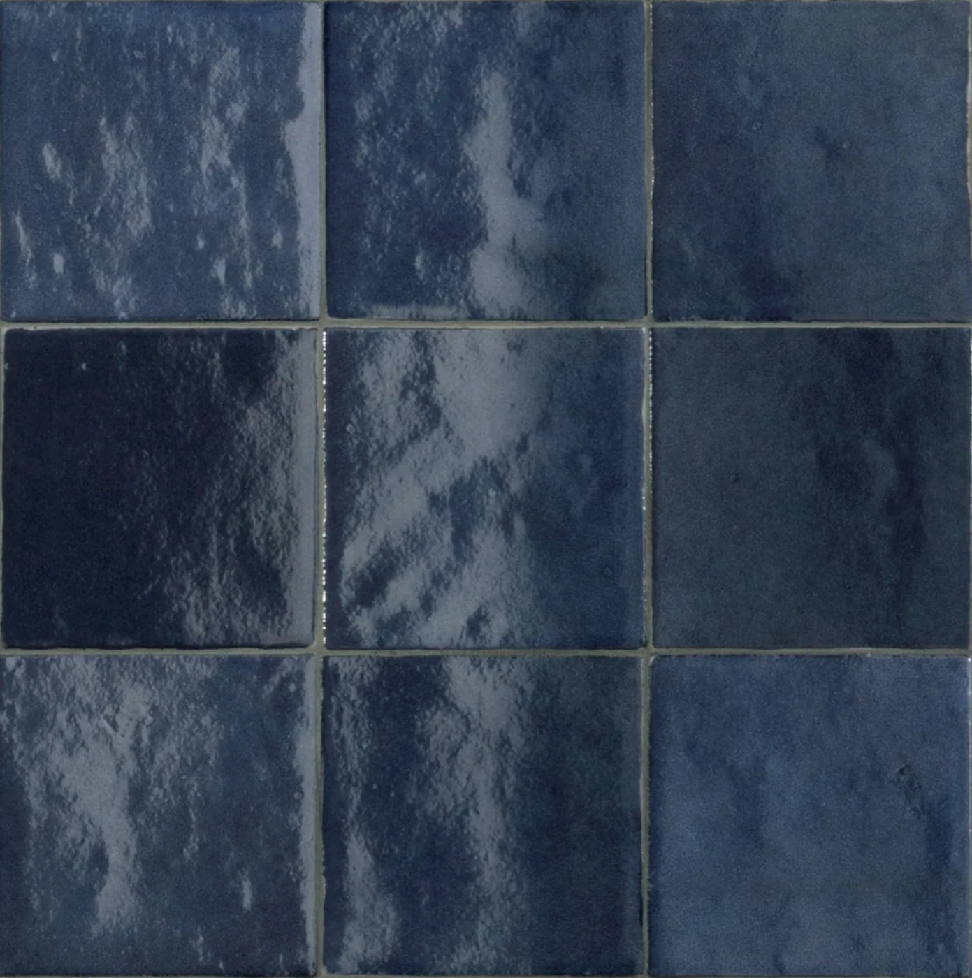 Glänzende Wandfliesen 10x10 cm in Marineblau, die unebene Glasur spiegelt das Licht in hellen Flecken