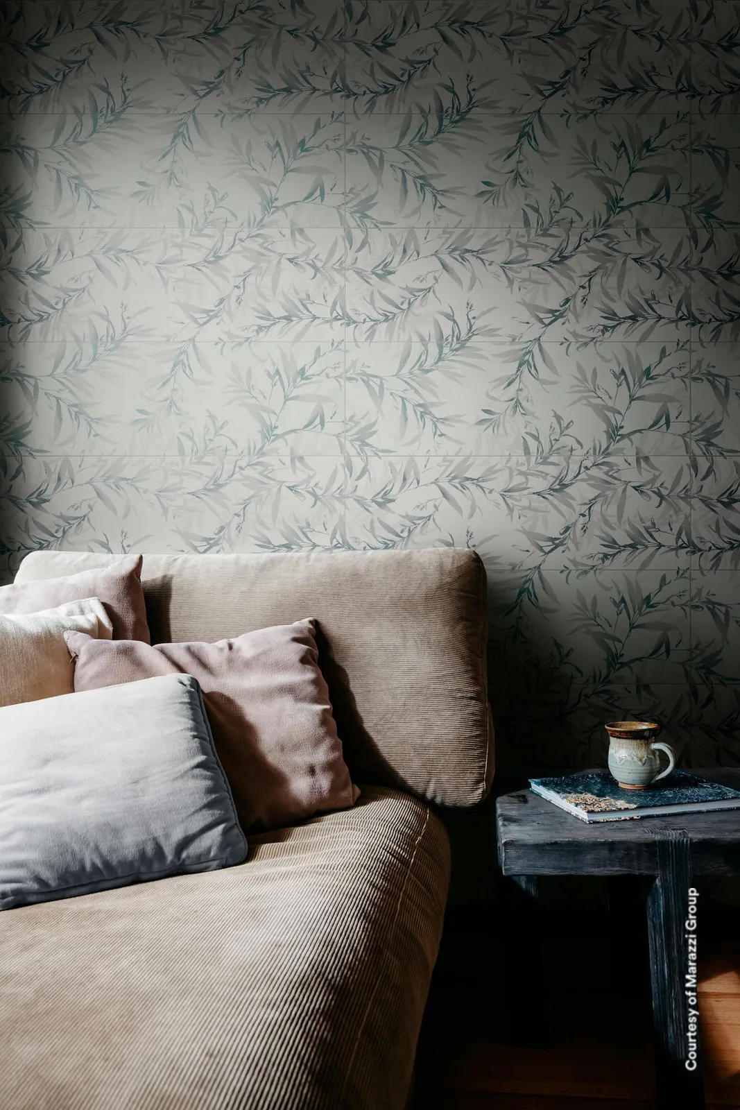 Wohnraum mit Sofa vor einer Wand aus Dekorfliesen Foliage White 50x76 cm mit blaugrauen Blattranken