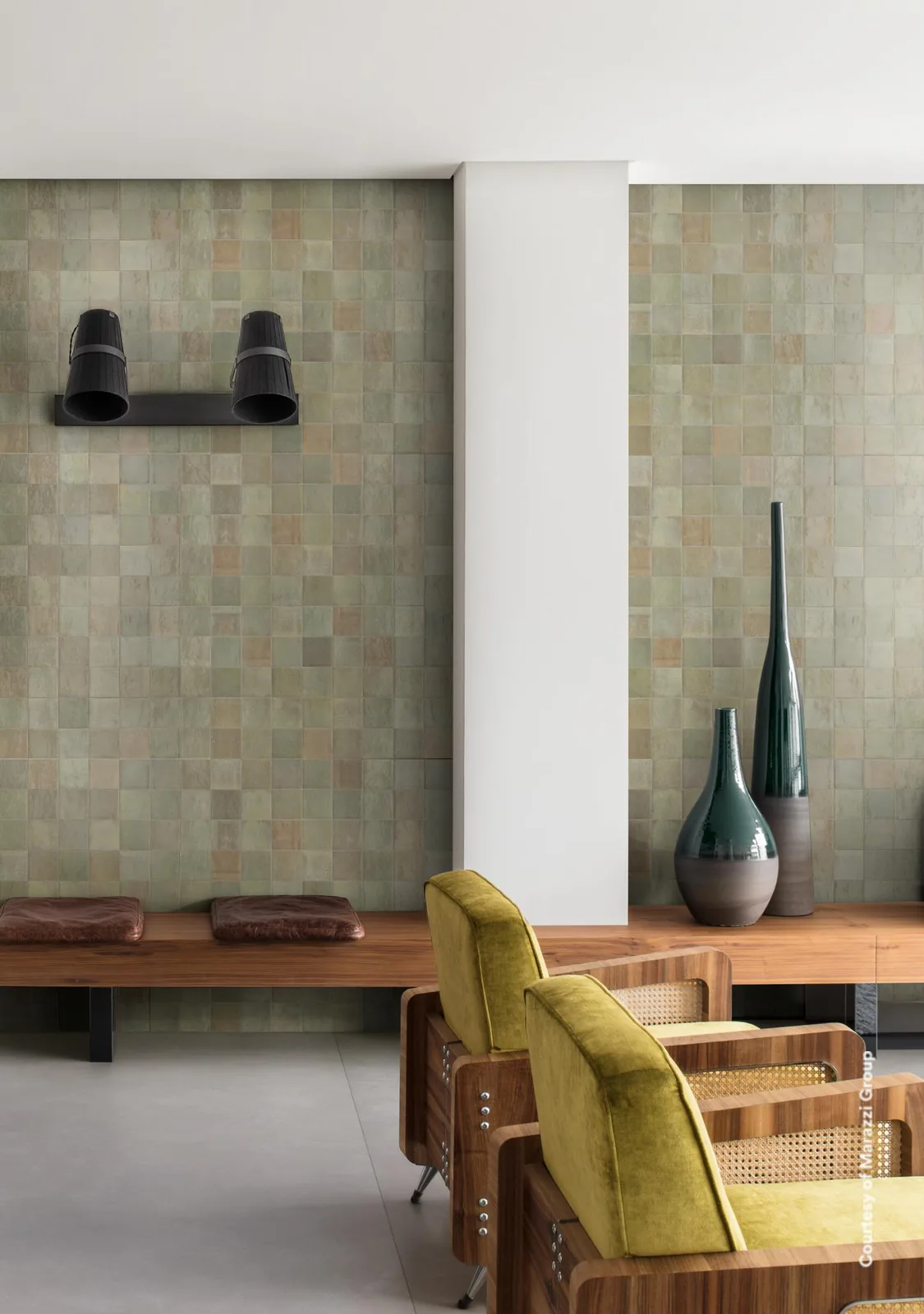 Wohnraum mit Wand aus Marazzi Zellige Salvia 10x10 cm in Salbeigrün, davor Holzbank und gelbe Sessel