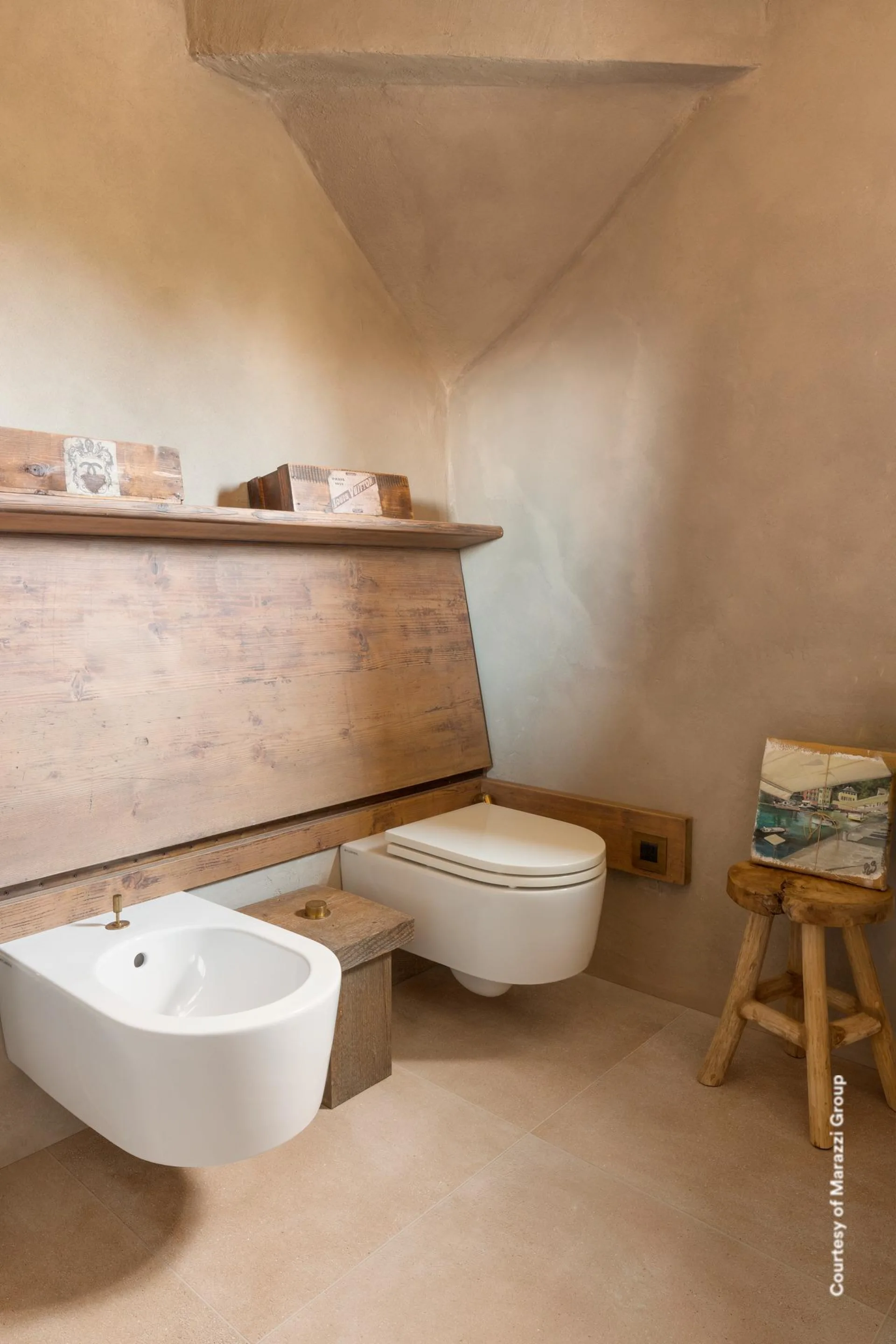 Bad mit Dachschräge, wandhängendem WC und Bidet, Holzablage und hellbeigem Betonoptik-Boden in Großformat.