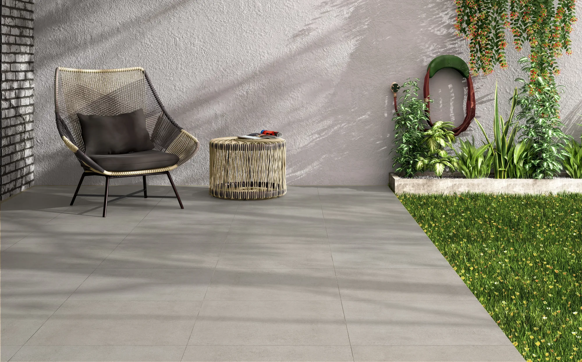 Terrasse mit hellgrauen Paleo-Fliesen 60x60, Loungesessel, kleinem Beistelltisch, Rasenkante und Pflanzen.