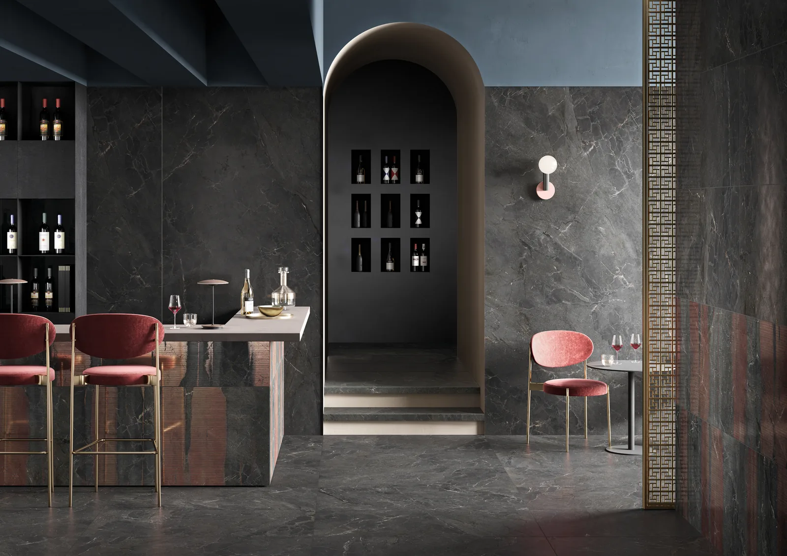 Bar mit anthrazitgrauen Marmoroptik-Fliesen an Boden und Wand, Theke mit kupferfarbenen Streifen und roten Barhockern.