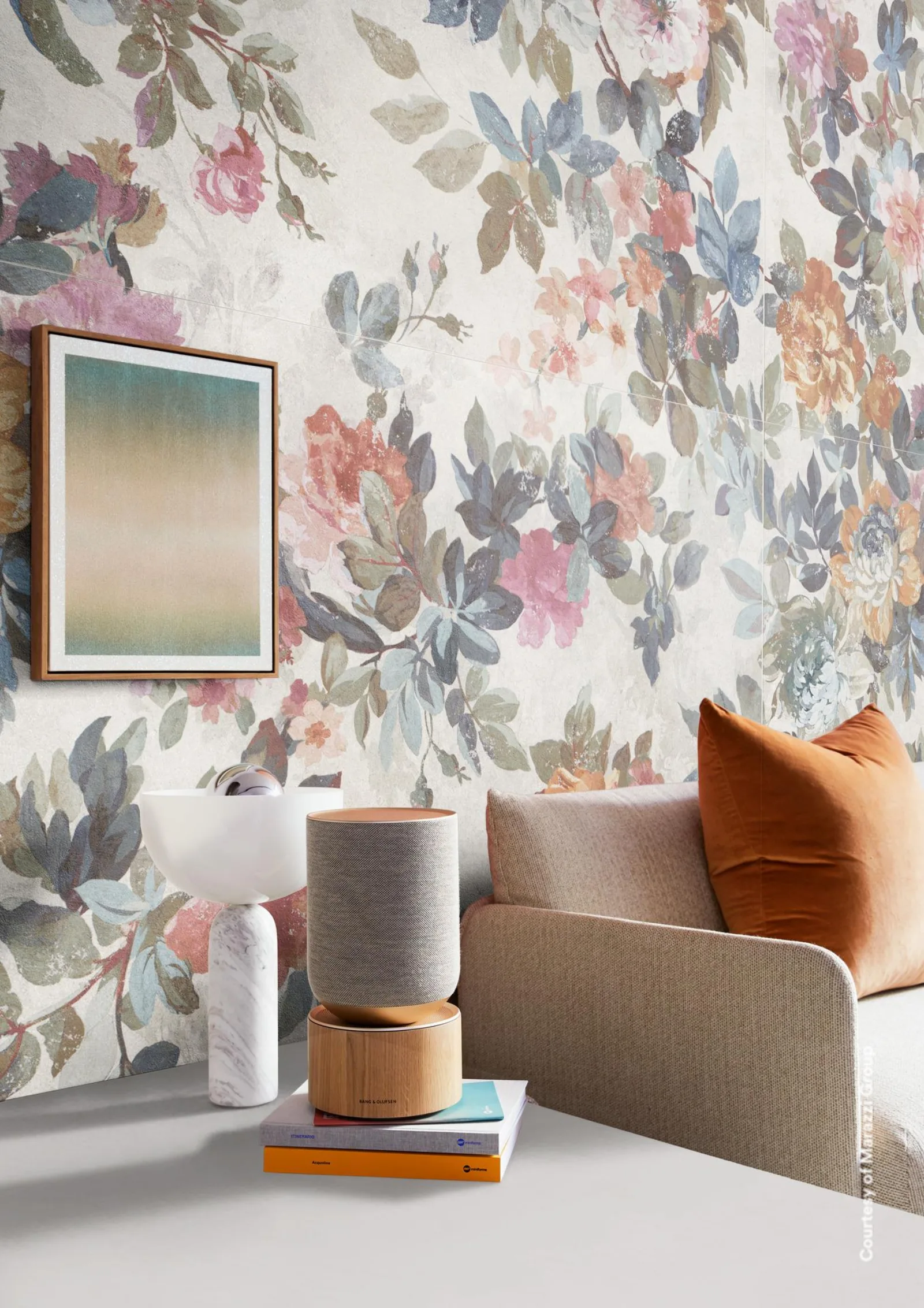 Sitzecke mit Sofa, Bild und Vasen vor einem großformatigen Wandpaneel mit Blüten in Rosa, Blau und Grau.