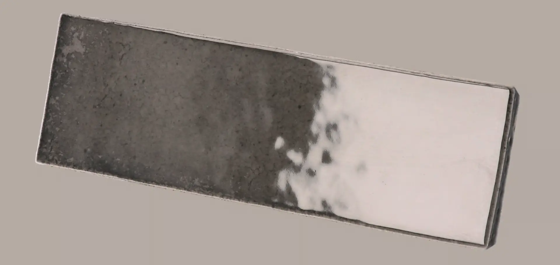 Hanoi Wandfliese in Black Ash Glasur, Format 5,1x16,1 cm, schräge Studio Aufnahme mit sichtbarem Glasurglanz.