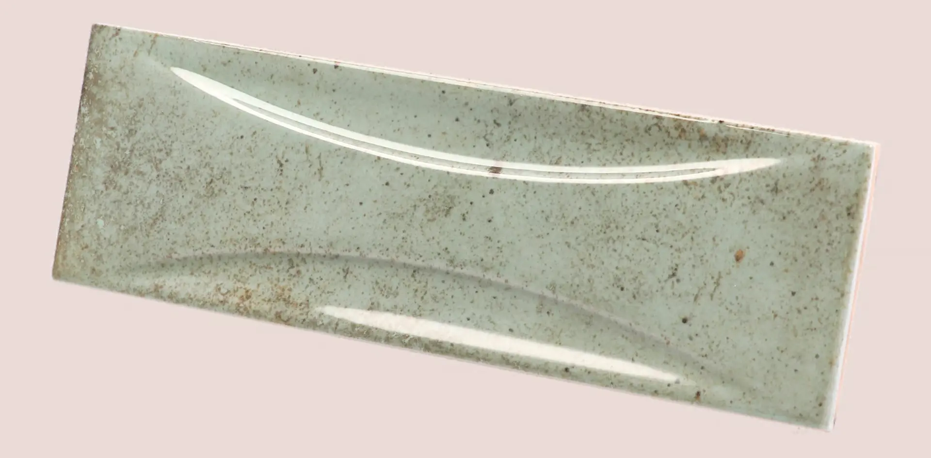 Hanoi Wandfliese in Celadon Glasur, Format 6,5x20 cm, schräge Studio Aufnahme mit sichtbarem Glasurglanz.