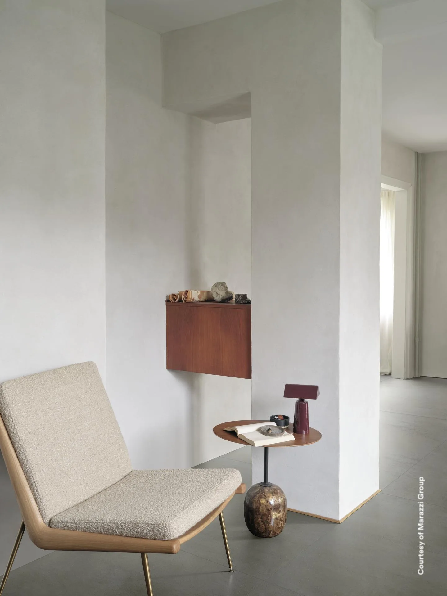 Sitzecke mit Loungesessel, Wandkonsole und Beistelltisch auf graugrünem Betonoptik-Boden in Salbei-Ton, Großformat.
