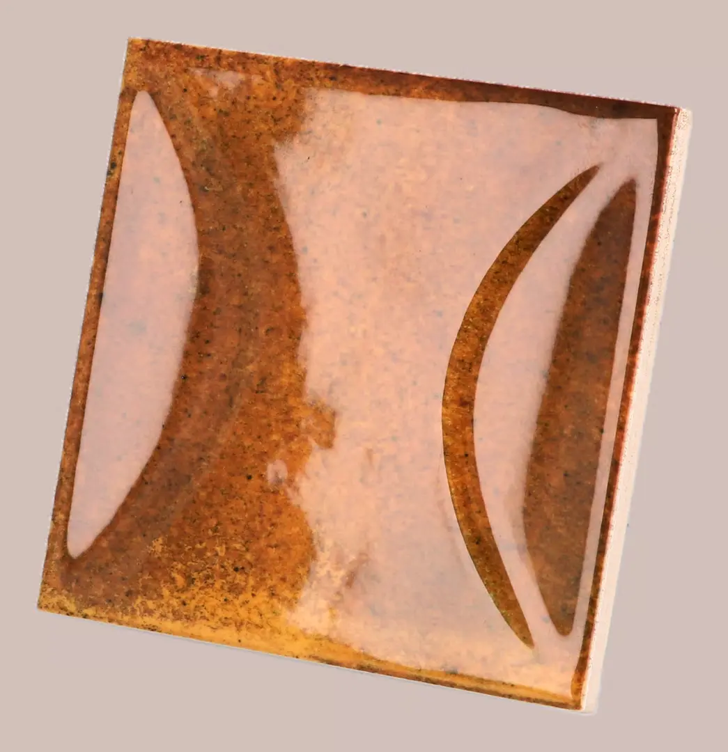 Hanoi Wandfliese in Burnt Red Glasur, Format 10x10 cm, schräge Studio Aufnahme mit sichtbarem Glasurglanz.
