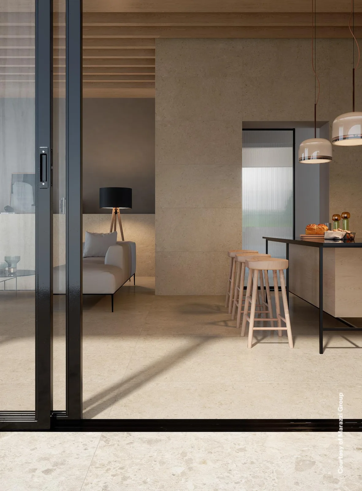 Offene Küche mit Theke und Hockern, Boden in heller Terrazzo-Optik, Wände in greigefarbener Steinoptik.