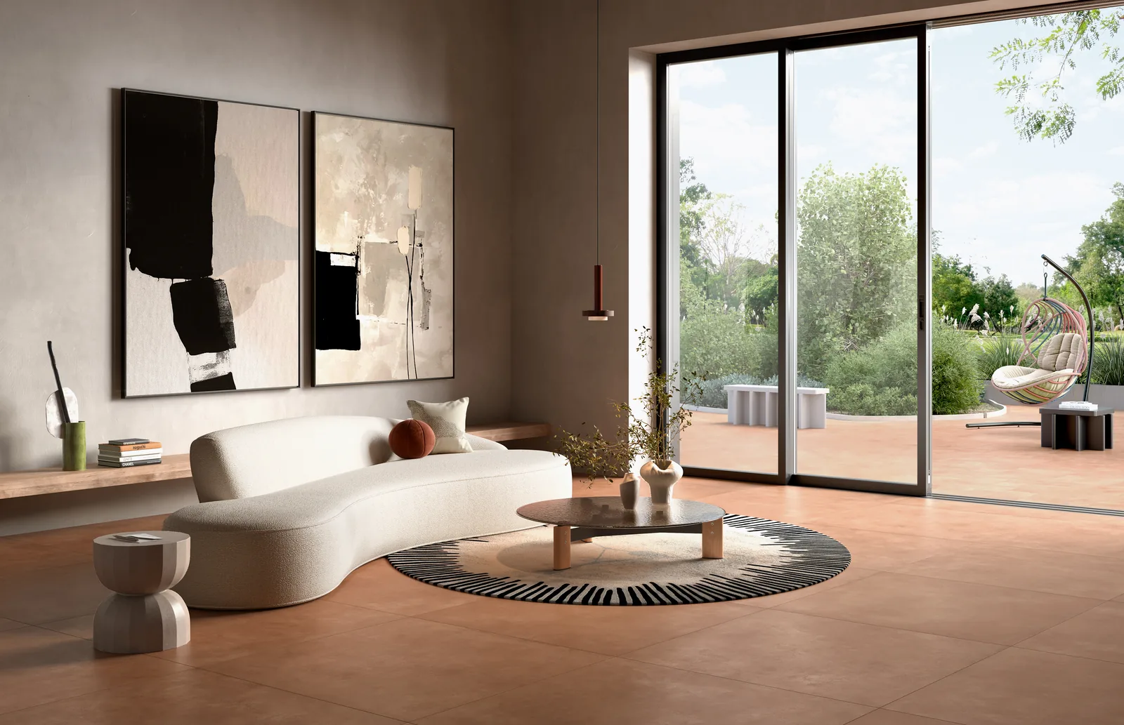 Wohnzimmer mit orangebraunem Großformat-Boden, weißem Sofa, großen Wandbildern und Glasfront zum Garten