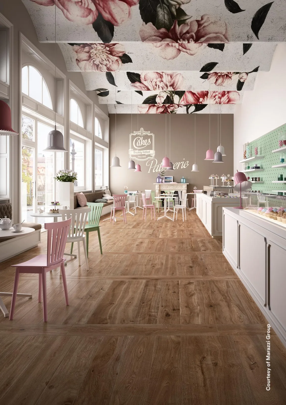 Langgestrecktes Café mit Blumenmotiv an der Decke, pastellfarbenen Stühlen und Theke auf braunen Holzoptik-Dielen.