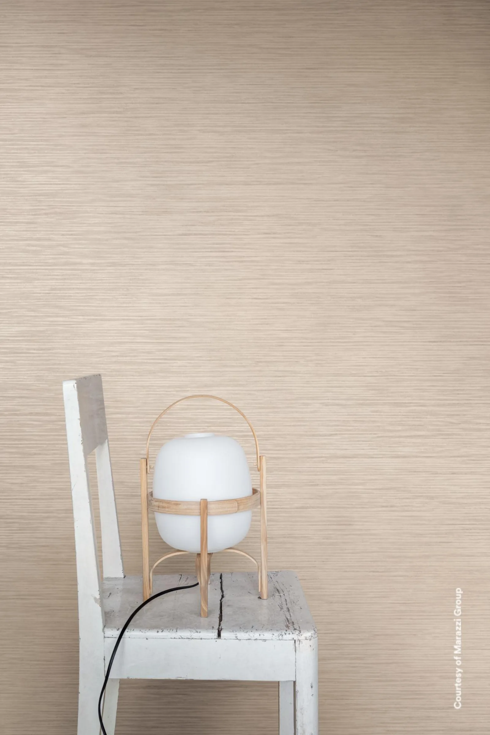 Marazzi Alchimia Fango Struttura Raw 60x180 cm: warm beige Wand mit feiner waagerechter Riffelung, Stuhl mit Leuchte.