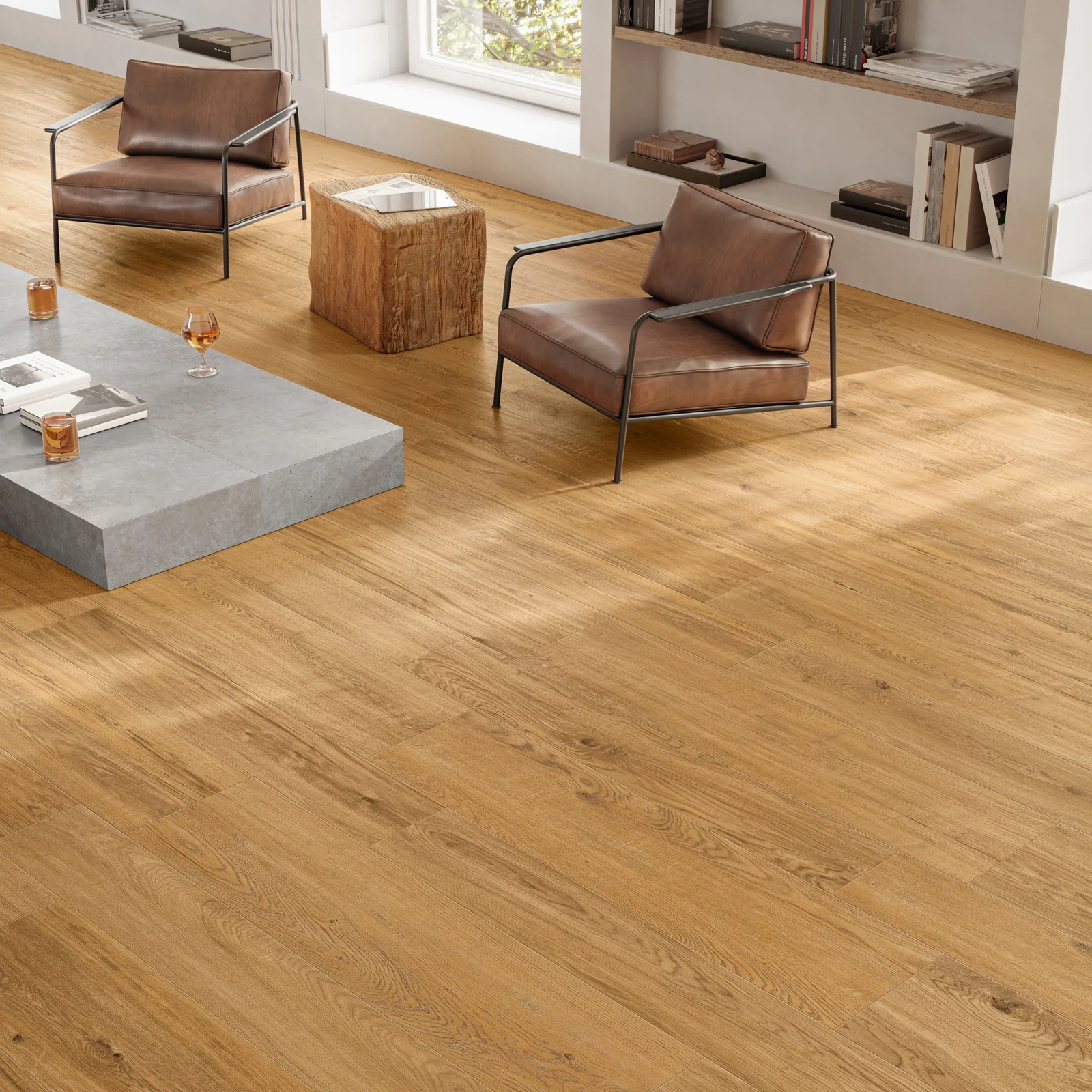 Wohnbereich mit karamellbraunem Holzoptik-Boden, zwei Ledersesseln, Holzhocker und grauem Couchtisch