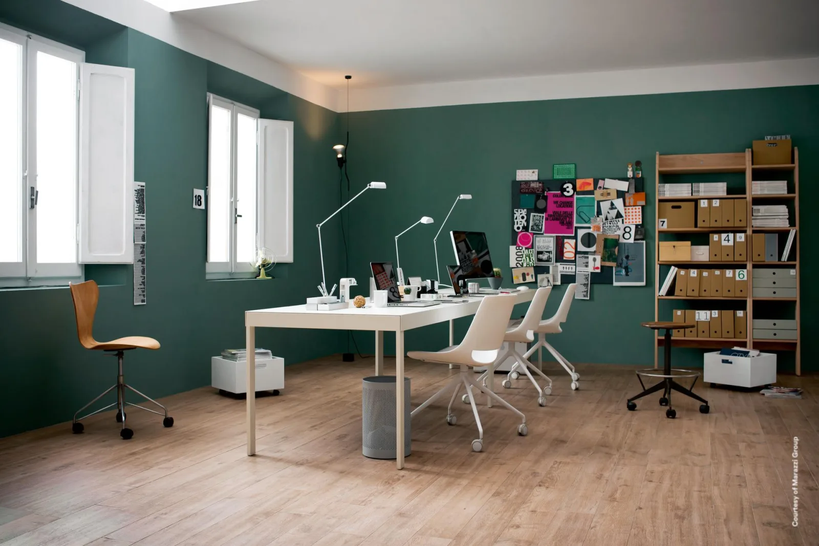 Arbeitszimmer mit mittelbraunem Dielenboden in Holzoptik, grüner Wand, weißen Schreibtischen und Bürostühlen.