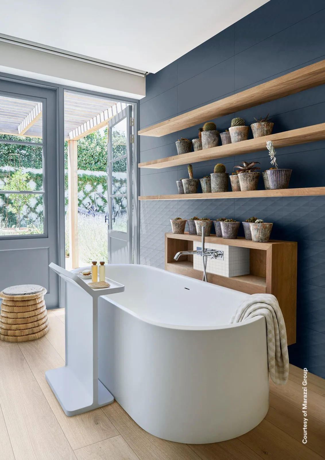 Bad mit rauchblauer Wand und Holzregalen über einer frei stehenden Wanne vor der Terrassentür