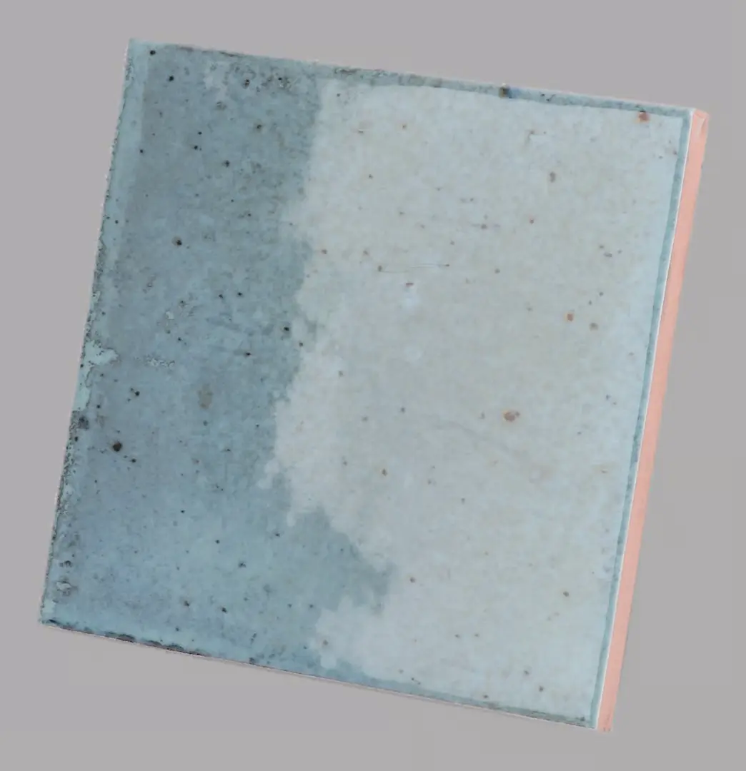 Hanoi Wandfliese in Sky Blue Glasur, Format 10x10 cm, schräge Studio Aufnahme mit sichtbarem Glasurglanz.