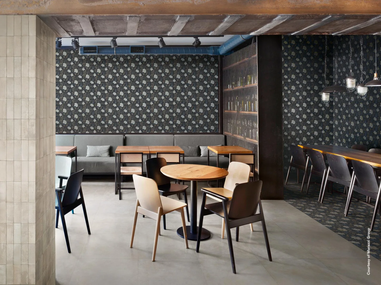 Restaurant mit Wanddekor aus weißen Lilien auf dunkelblauem Grund hinter Tischen und Polsterbank, dazu ein heller Boden.