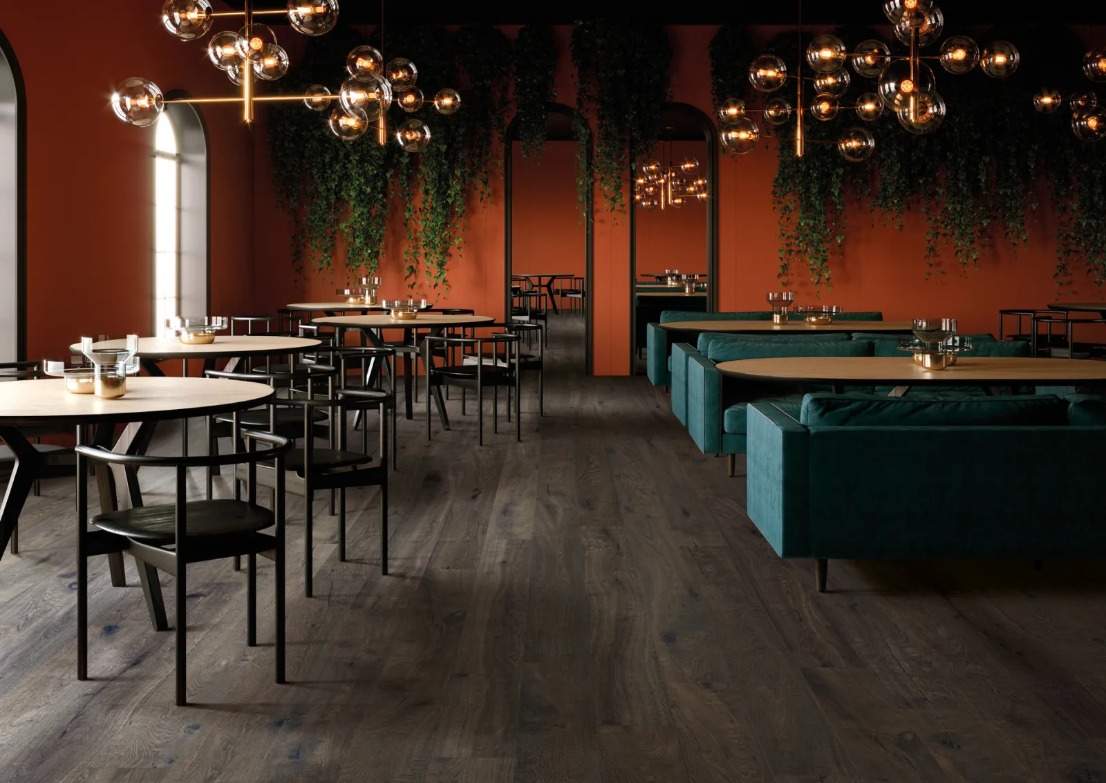 Restaurant mit roten Wänden, grünen Samtsofas und Kugelleuchten auf Dielenboden in fast schwarzbrauner Holzoptik.