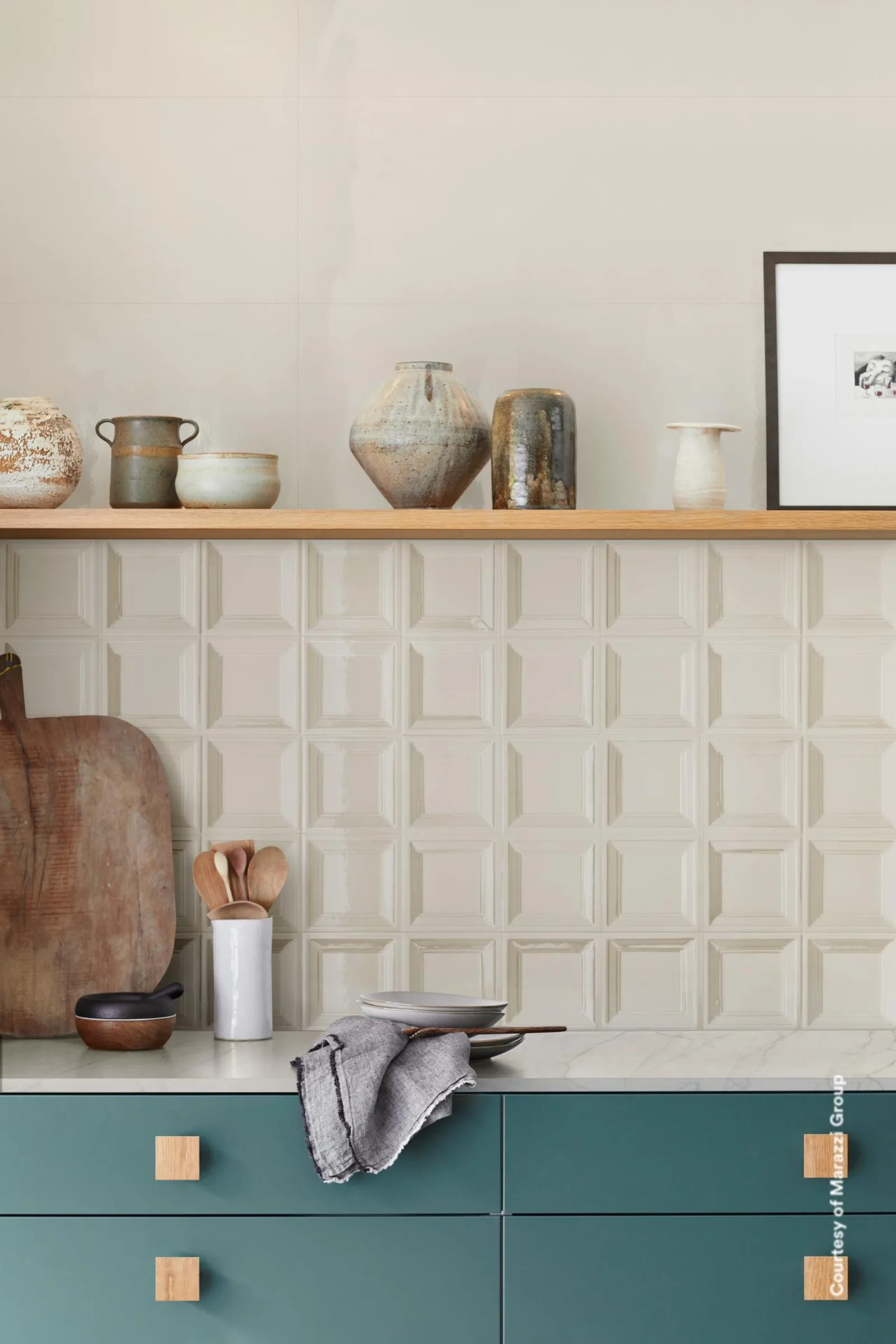 Marazzi Bliss 3D Square Cream: Küche mit cremefarbenem Kassettenrelief als Rückwand, petrolgrünen Fronten und Holzregal