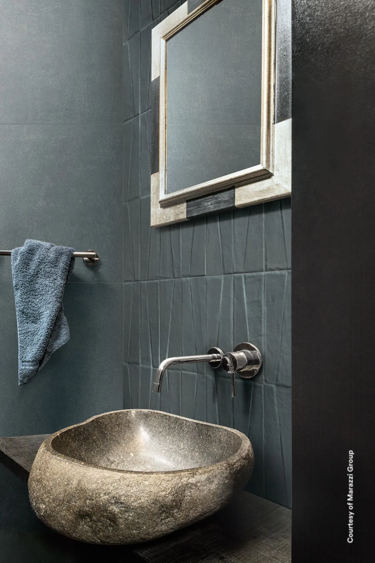 Gäste-WC mit dunkelblauer Wand, unten mit Trapez-Relief, Waschschale aus Naturstein, Wandarmatur und Spiegel mit Metallrahmen