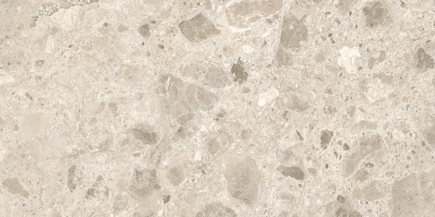 Beige Fliese 30×60 cm in Terrazzo-Optik mit grauen und hellen Steinsplittern unterschiedlicher Größe auf heller Fläche.
