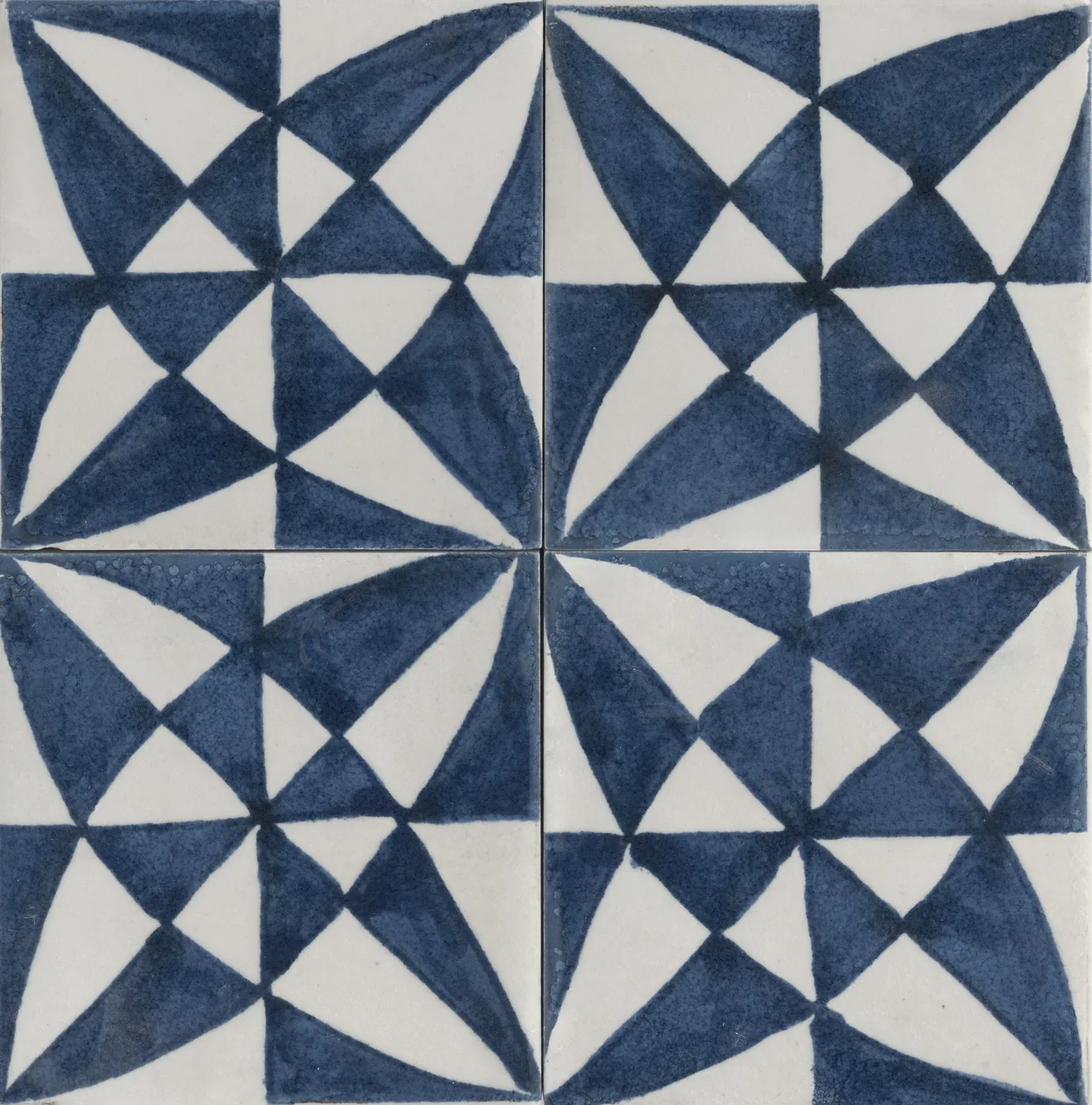 Vier glänzende Fliesen 15x15 cm mit geometrischem Dreiecksmuster in Blau und Weiß, zusammen ein Windradstern.