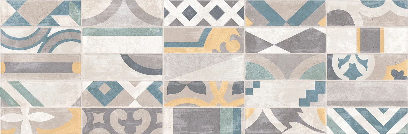 Wandfliese 25×76 cm mit buntem Patchworkmuster aus geometrischen Feldern in Blau, Gelb und Grau.