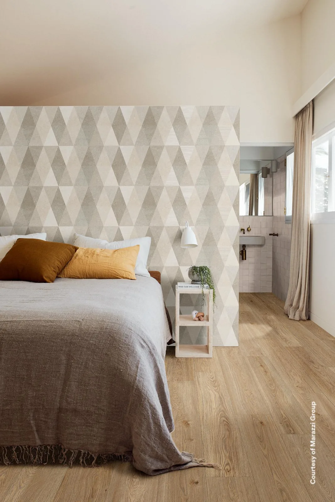 Schlafzimmer mit Wandverkleidung im Rautenmuster aus hellen Beigetönen hinter dem Bett, davor Holzboden und Leinen.